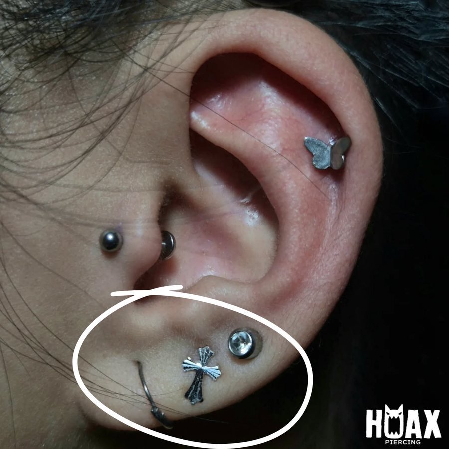 Lobe piercings with a cross stud and crystal stud